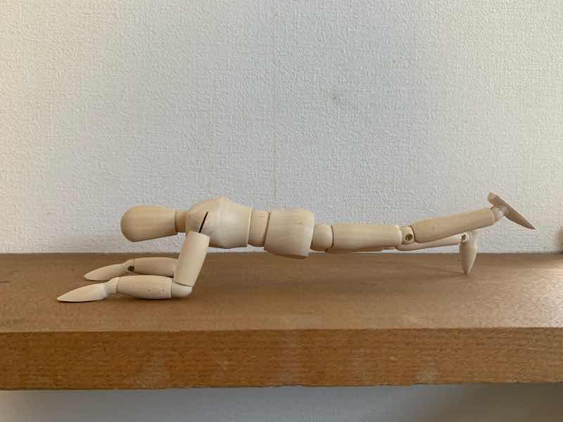 体幹トレーニングの基本的なトレーニングとしての片足プランク(ワンレッグプランク)をしている人形の写真です。